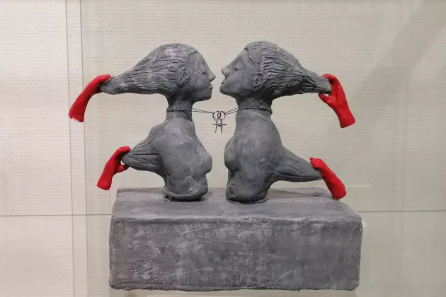 En stenskulptur av två ansikten vända mot varandra. Foto.