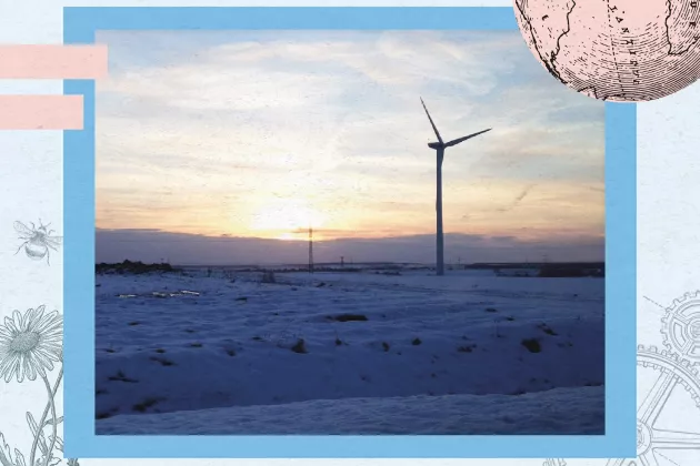 Ett vindkraftverk i ett snölandskap i solnedgång. Foto.