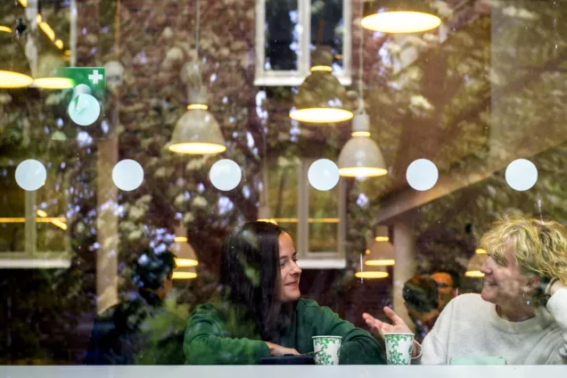 Två personer sitter på café med kaffemuggar. Foto.