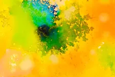 Närbild på akvarellfärg målat på papper i gul, grön, orange och blå. Foto.