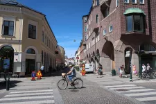 En person cyklar på en väg omgiven av stenhus. Foto.